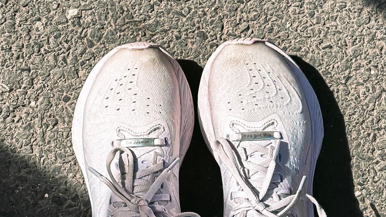 Running shoes with lace clips reading 'Go Jasmin' and 'You got this'